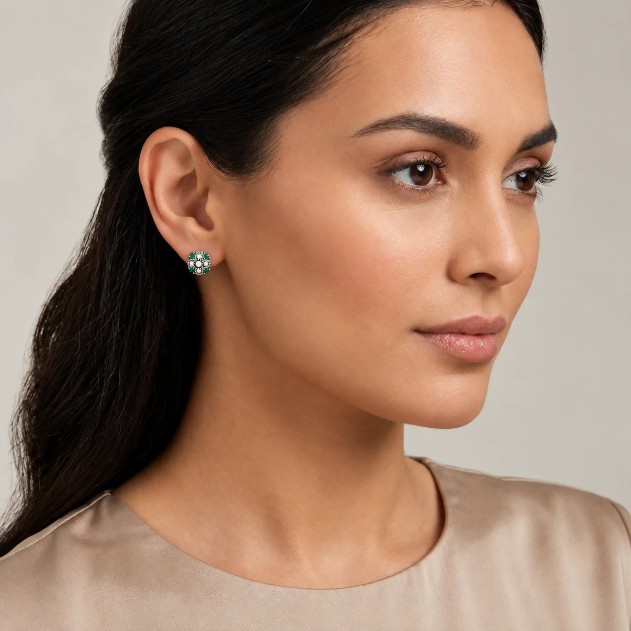 Close-up of a woman wearing one silver emerald and freshwater seed pearl stud earring.
