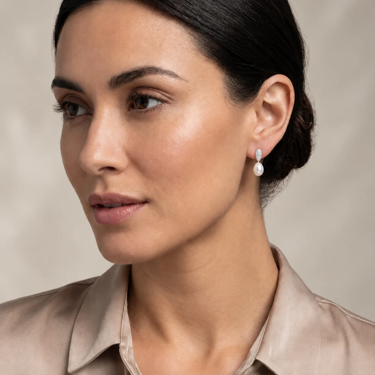 Close-up of a woman wearing silver freshwater cultured pearl and cubic zirconia studded earrings.