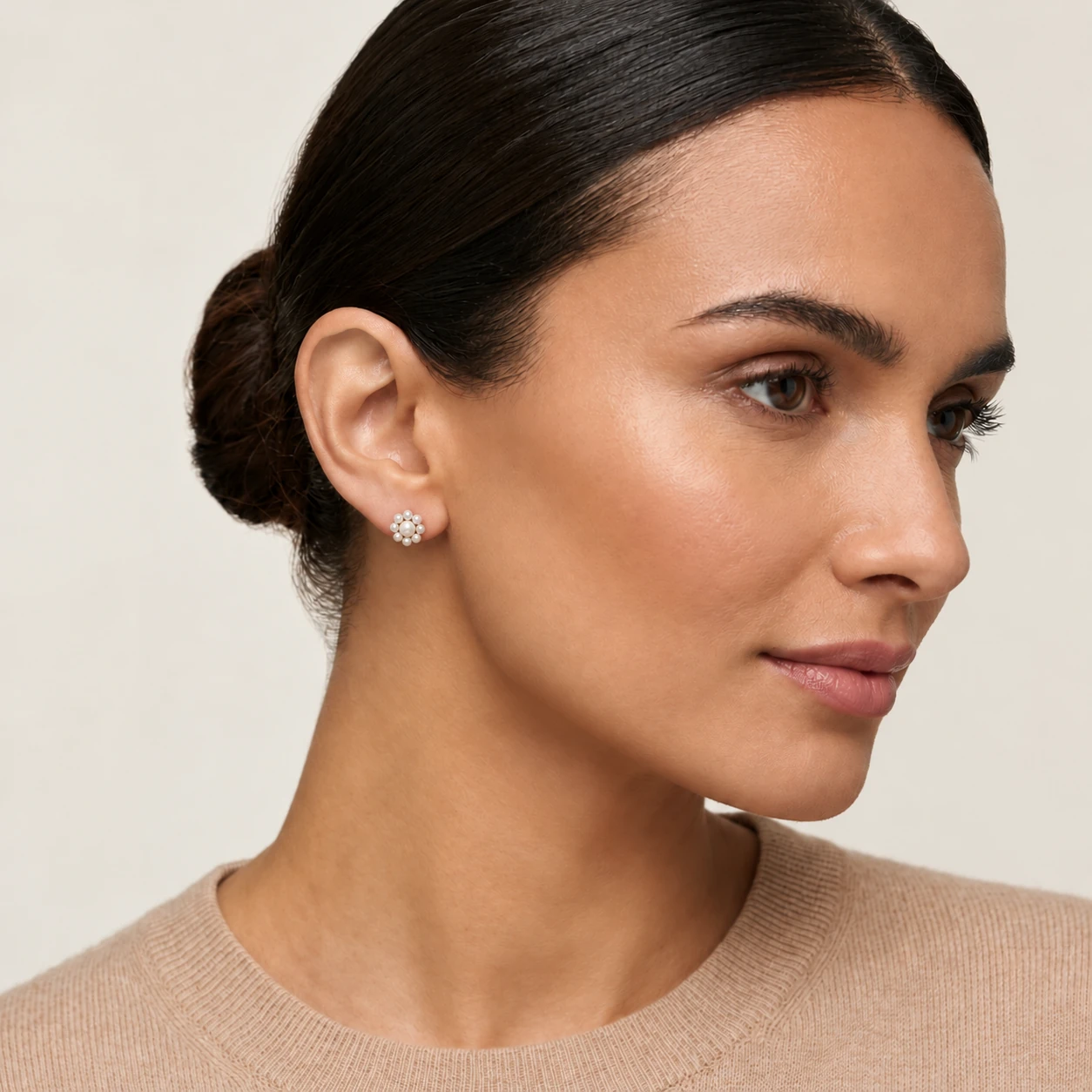 Close-up of a woman wearing a silver freshwater cultured pearl cluster earring, shaped like a flower.