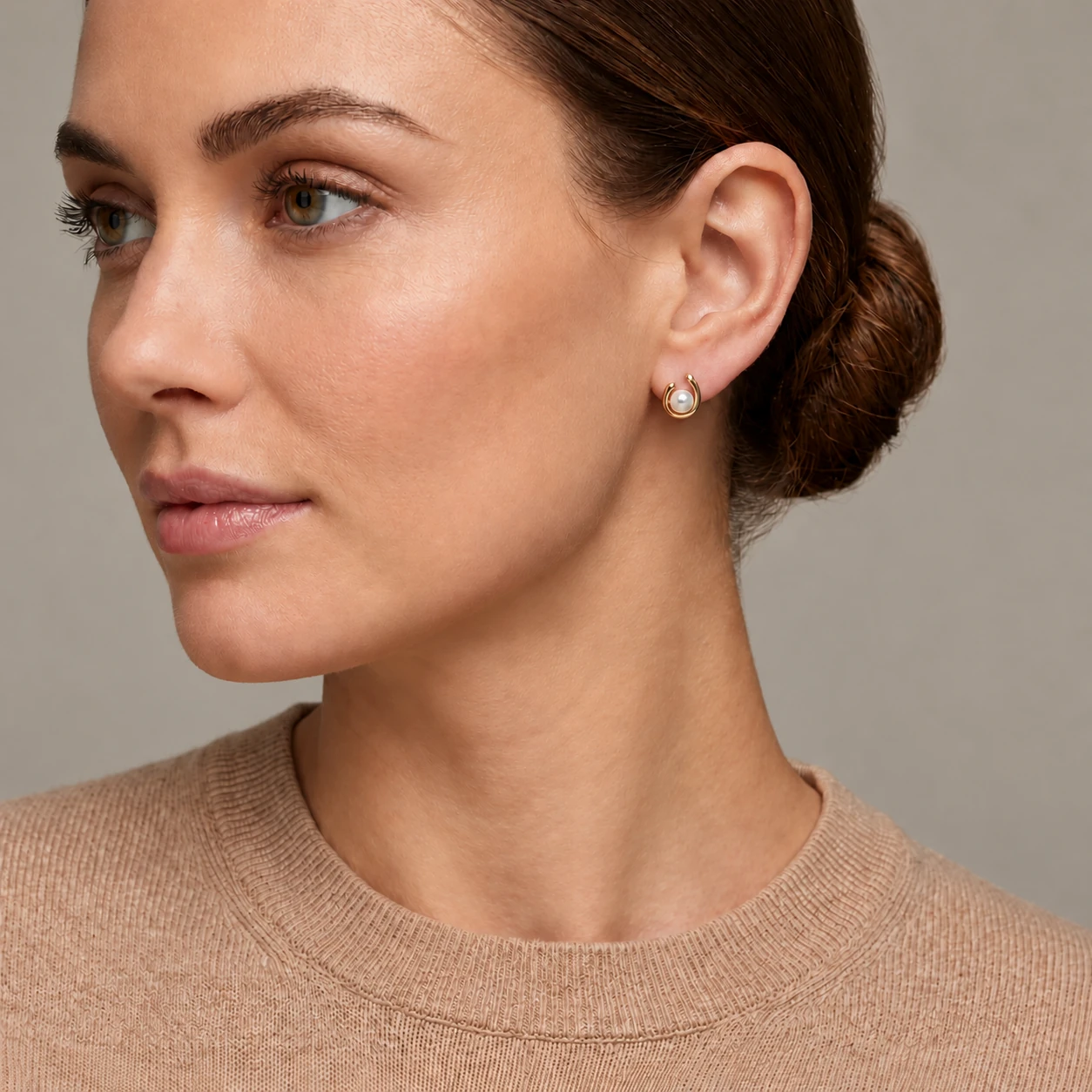 Close-up of a model wearing 9ct gold freshwater pearl & diamond loop stud earrings.